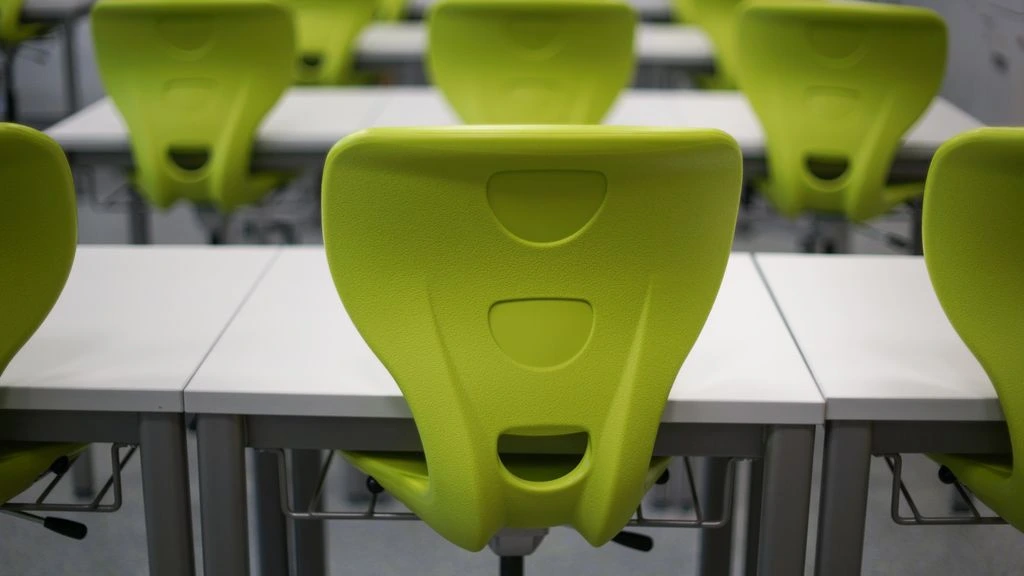 A row of classroom desks each holding a printed WeeklyCalendar planner.